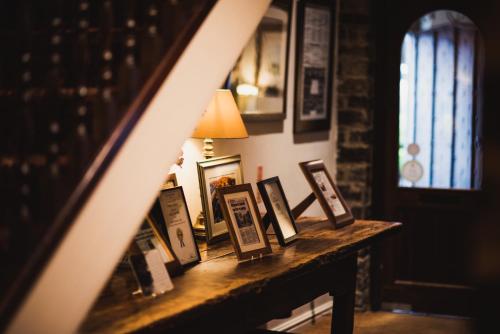 a table with framed pictures on it with a lamp at Holdsworth House Hotel in Halifax