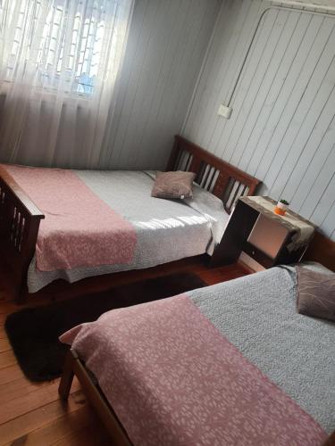 two twin beds in a room with a window at Cabañas casa blanca in Laraquete