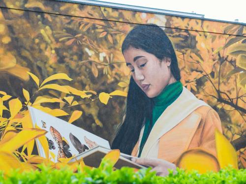 a woman reading a book in front of a painting at Mercure Metz Centre in Metz