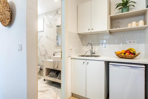 a kitchen with white cabinets and a bowl of fruit at Almira Hotel in Troulos