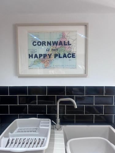 a bathroom with a sink and a happy place picture at Forge Cottage in Polperro