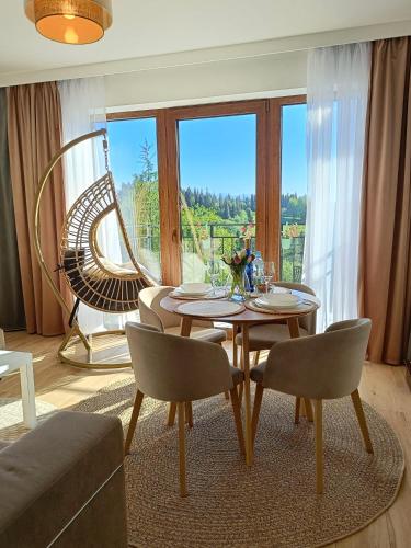 a living room with a table and chairs and a large window at Apartament Dwa Słońca in Gliczarów