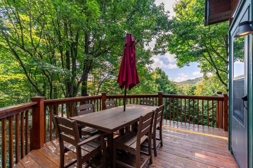 a wooden table with chairs and an umbrella on a deck at Windswept Vistas in Boone
