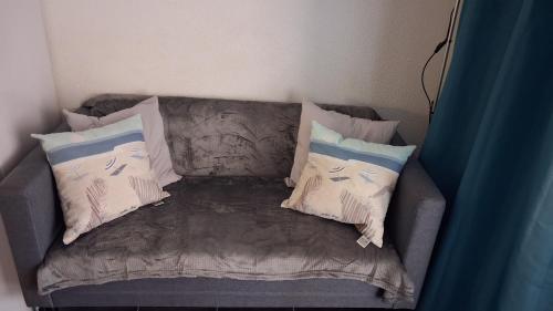 a couch with pillows on it in a room at Parc résidentiel Les Moussaillons in Hourtin