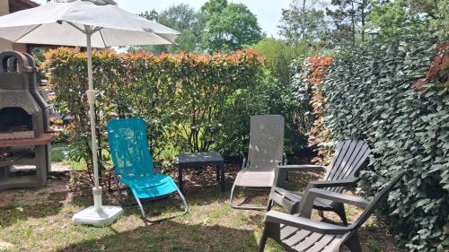 a group of chairs and an umbrella in a yard at Parc résidentiel Les Moussaillons in Hourtin