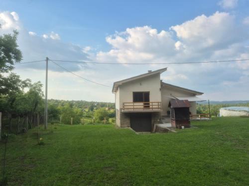 a small house in a field with a green yard at Domacinstvo Pecina Petnica in Petnica