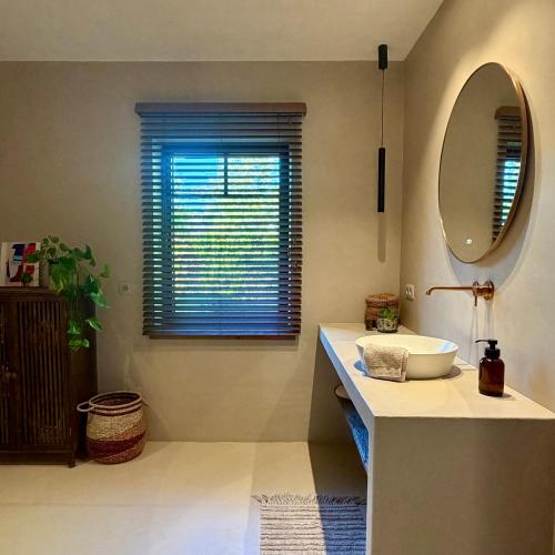 a bathroom with a sink and a mirror and a window at La Petite Suite - Unique Guesthouse in Schilde