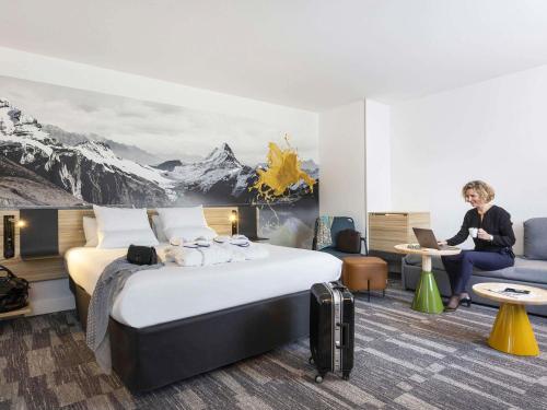 a woman sitting at a desk in a hotel room at Novotel Annecy Centre in Annecy