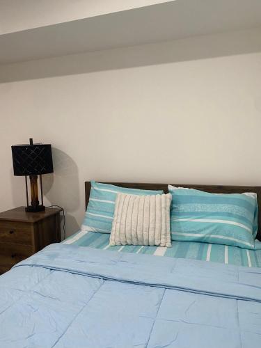 a bed with blue and white pillows and a lamp at Sakisa International in Waldorf