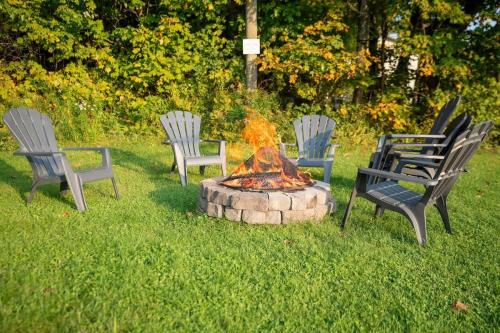 a group of chairs sitting around a fire pit at Rustic Chalet Hideaway - Hot Tub & Trail Access in Saint-Léonard-de-Portneuf