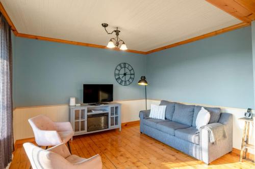 a living room with a couch and a tv at Rustic Chalet Hideaway - Hot Tub & Trail Access in Saint-Léonard-de-Portneuf