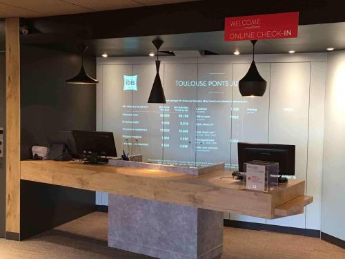 a lobby with a counter with two computers on it at ibis Toulouse Pont Jumeaux in Toulouse