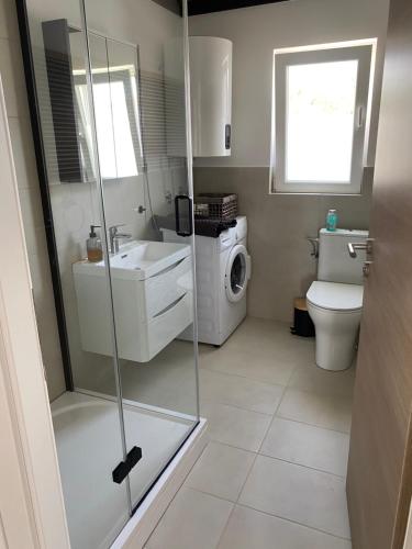 a bathroom with a shower and a sink and a washing machine at Apartment Eleni in Šibenik