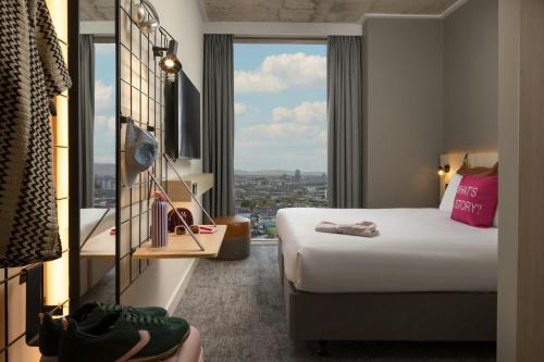 a hotel room with a bed and a large window at Moxy Dublin Docklands in Dublin