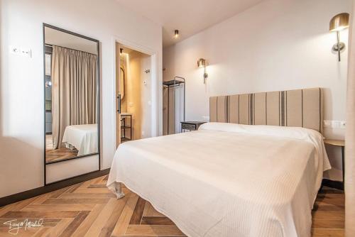 a bedroom with a large white bed and a mirror at La Cepa Apartamentos in Alhama de Granada