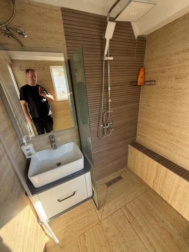 a man taking a picture of himself in a bathroom mirror at Villa ADUSHI Nashec in Prizren