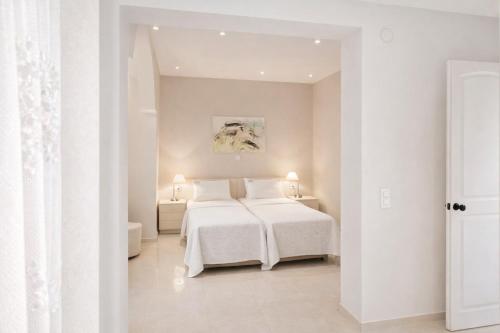 a white bedroom with a white bed and two tables at green & blue villa in Glykadi