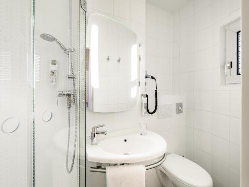 a white bathroom with a sink and a shower at ibis Hotel München City in Munich