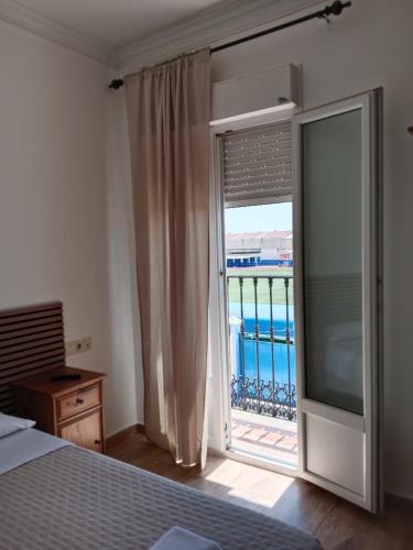 a bedroom with a sliding glass door to a balcony at Hostal Alcarayón Pilas in Pilas