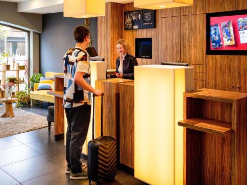 a man standing at a counter in a lobby with a woman at ibis Leuven Centrum in Leuven