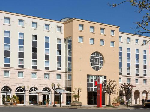 a large building with a red sign in front of it at ibis Vichy in Vichy