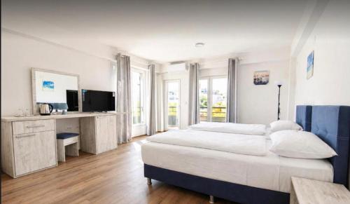 a white bedroom with a large bed and a television at Mia Apartment in Veles