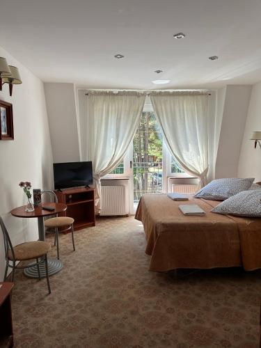 a bedroom with a bed and a television and a table at Pensjonat Perła in Pobierowo