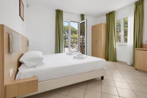 a bedroom with a large white bed and windows at Borgo al Mare in Marina di Bibbona