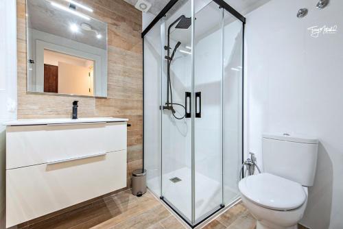 a bathroom with a toilet and a glass shower at La Cepa Apartamentos in Alhama de Granada