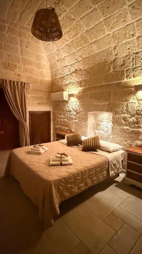 a bedroom with a large bed in a stone wall at Luxury Vittoria in Ceglie Messapica