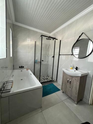 a bathroom with a tub and a shower and a sink at Exquisite cottage in Doringkloof in Centurion