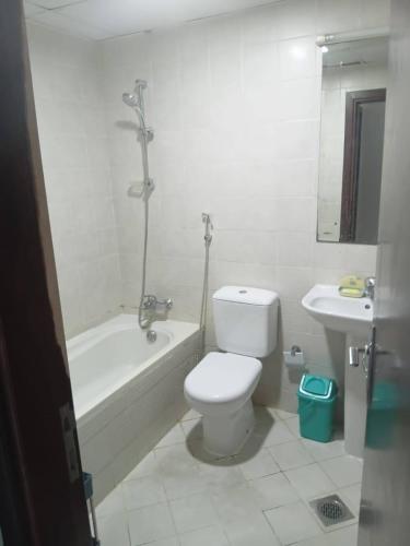 a bathroom with a toilet and a tub and a sink at Relaxing bed Ajman in Ajman 