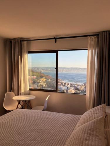 a bedroom with a large window with a view of the ocean at Hotel Camino del Alto Reñaca in Viña del Mar