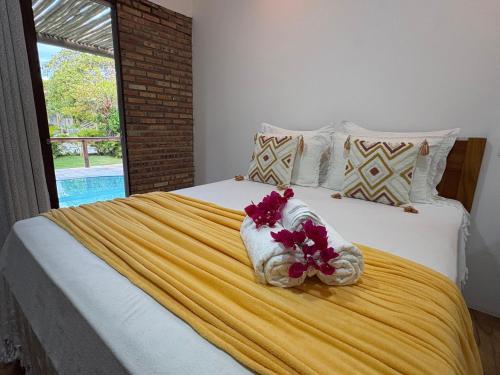 a bedroom with a bed with towels and flowers on it at Chalés Refúgio Fortim in Fortim