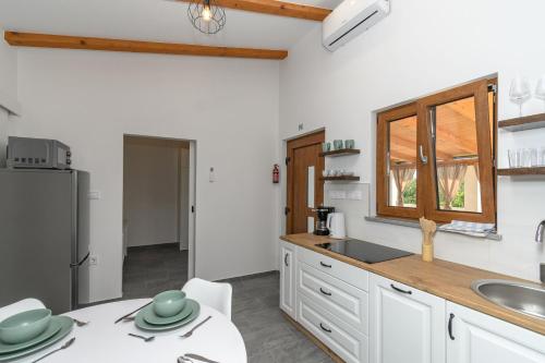 a kitchen with white cabinets and a sink and a refrigerator at House Guesthouse Stipe in Lopar