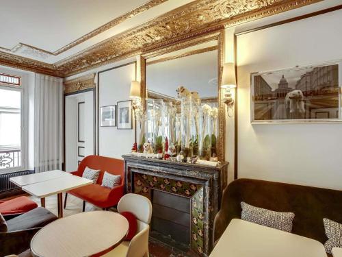 a room with a fireplace and tables and chairs at Mercure Paris Opera Louvre in Paris