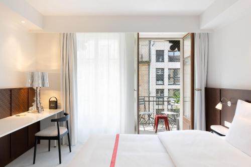 ein Schlafzimmer mit Bett, Schreibtisch und Balkon in der Unterkunft Ruby Claire Hotel Geneva by IHG in Genf