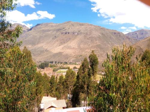 a mountain in the distance with a town and trees at Hatun Apu Center Casa de Ayahuasca y San Pedro in Pisac