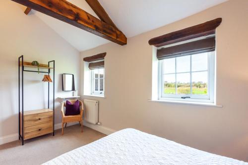 a bedroom with a bed and a window and a chair at Carleton Mill Cottage in Carlisle
