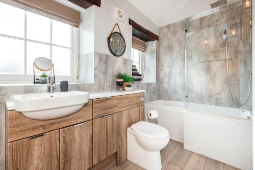 a bathroom with a sink and a toilet and a tub at Carleton Mill Cottage in Carlisle