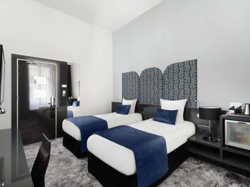 a hotel room with two beds and a tv at Nemzeti Hotel Budapest - MGallery Collection in Budapest