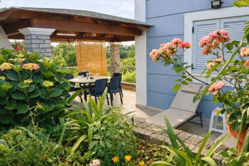 a patio with a table and chairs and flowers at Villa Nirvana - Sea View Maisonette in Roda, Offering Tranquility and Comfort on the Enchanting Northern Coast of Corfu in (( Litherés ))