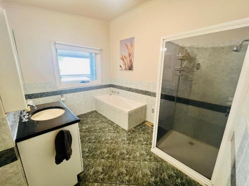 a bathroom with a tub and a sink and a shower at Treetops Escape Albury in Albury