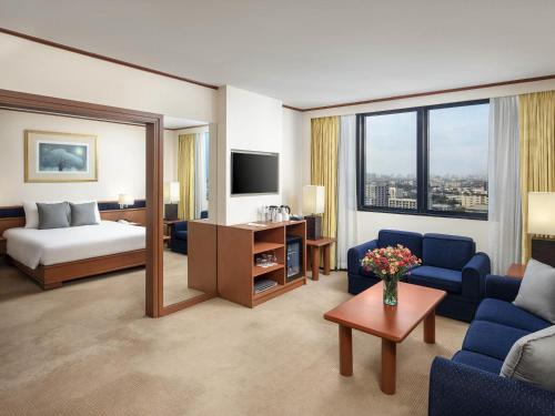 a hotel room with a bed and a living room at Novotel Bangkok Bangna in Bangna