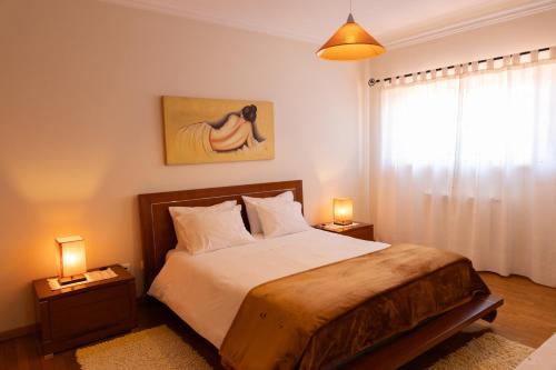 a bedroom with a bed with two lamps and a window at Quarto em Viana do Castelo in Viana do Castelo