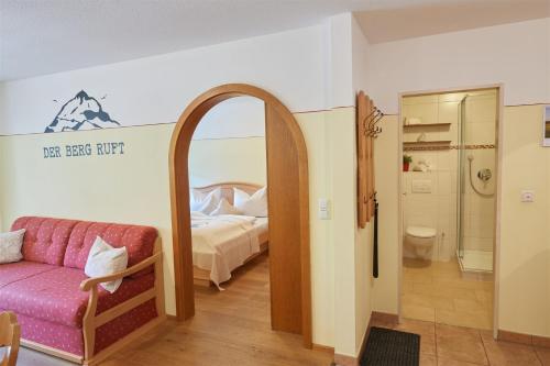 a room with a bed and a couch and a mirror at Gästehaus Gruber in Piding