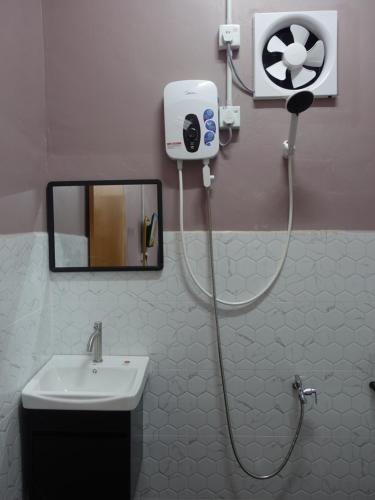 a shower in a bathroom with a sink and a fan at IA Tiny House in Kampong Sura Tengah