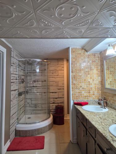 a bathroom with a shower and two sinks and a tub at Cozy Mobay in Hampton