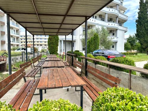 a row of wooden benches sitting under a pavilion at Apartments Perezaj II in Ulcinj