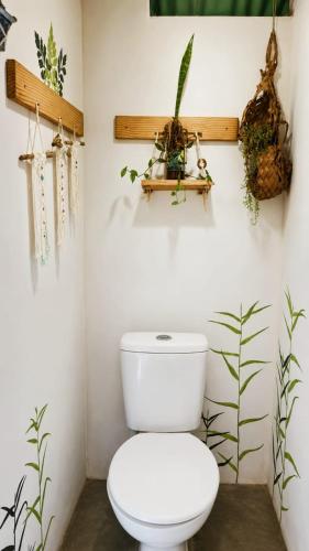 a bathroom with a toilet and plants on the wall at Kombi Hostel Camping in Vale do Capao